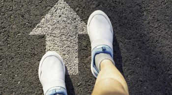 Top view of man wearing white shoes choosing a way marked with white arrows. Chooses the right path concept.