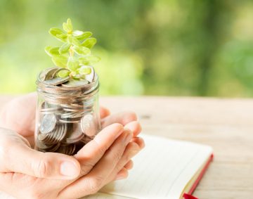 woman-hand-holding-plant-growing-from-coins-bottle