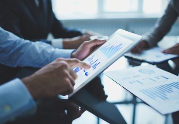 Image of businessperson pointing at document in touchpad at meeting