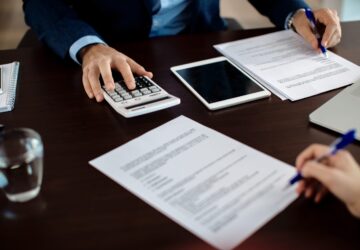Close-up of real estate agent calculating costs of a mortgage agreement while having a meeting with a client in the office.
