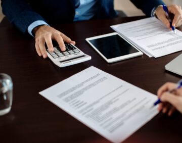 Close-up of real estate agent calculating costs of a mortgage agreement while having a meeting with a client in the office.