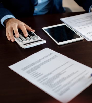 Close-up of real estate agent calculating costs of a mortgage agreement while having a meeting with a client in the office.
